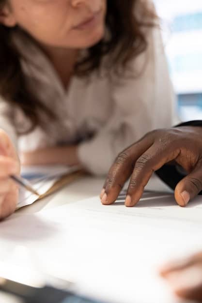 A close-up of a diverse group of hands holding pens and writing on college application forms, with a shallow depth of field to emphasize the focus and determination in preparing for college.
