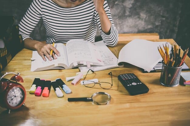 A student sitting at a desk, writing in a planner with a determined expression, surrounded by textbooks and a laptop, symbolizing goal setting and academic planning.
