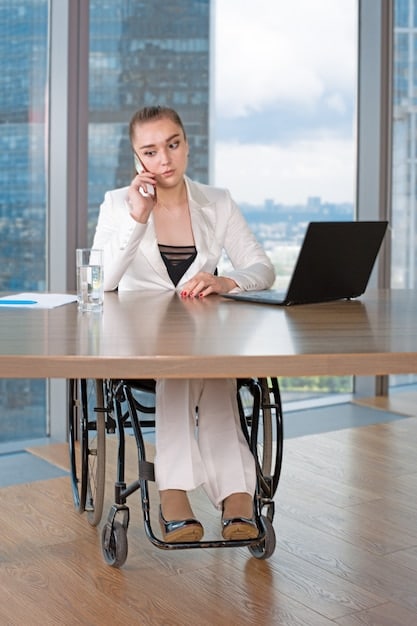 A person in a wheelchair working diligently on a laptop in a modern, accessible office environment, illustrating that disability doesn't always mean inability to work and the importance of supportive workplace policies.