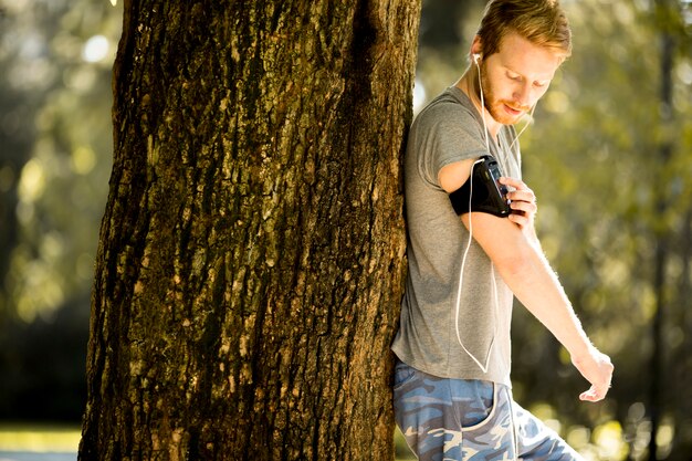 A person using a fitness tracker while jogging in a park. Sunlight filters through the trees, creating a peaceful and motivating atmosphere. The focus is on the tracker displaying health metrics.