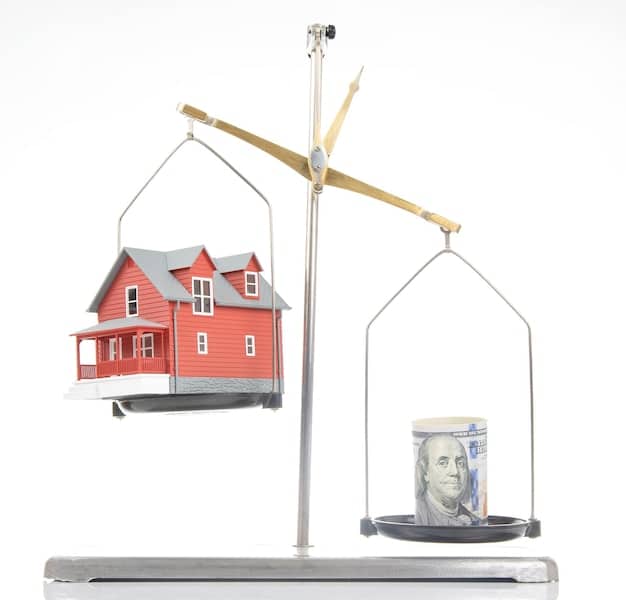 A close-up of scales of justice, balanced, with miniature houses on either side, illustrating fair housing practices.