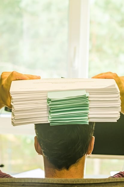 A person organizing various documents, such as pay stubs, credit reports, and recommendations, in a neat pile, symbolizing preparation for a housing appeal.