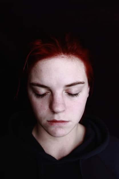 A close-up of a person's face, showing an expression of profound sadness and despair. Their eyes are downcast, and their face is pale. The lighting is dim and adds to the feeling of melancholy.