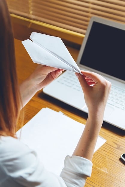 A close-up shot of a person's hands organizing receipts and financial documents on a desk with a laptop in the background displaying tax software.