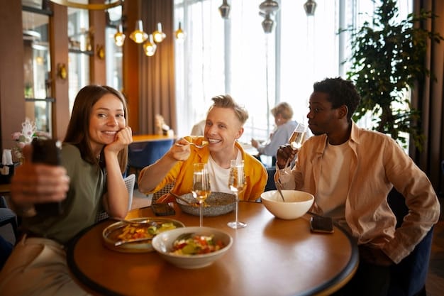 A group of friends laughing and sharing a meal together at a warmly lit restaurant. The atmosphere is jovial and supportive, with visible expressions of happiness and connection among the people.