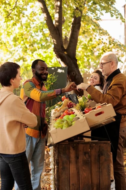 A family receiving a box of fresh produce at a food bank distribution event. The box is filled with fruits, vegetables, and other healthy food items.