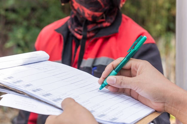 A close-up shot of a hand filling out a community resource application form, with a pen hovering over a specific section. The form includes checkboxes and fields for personal information, income, and eligibility criteria.