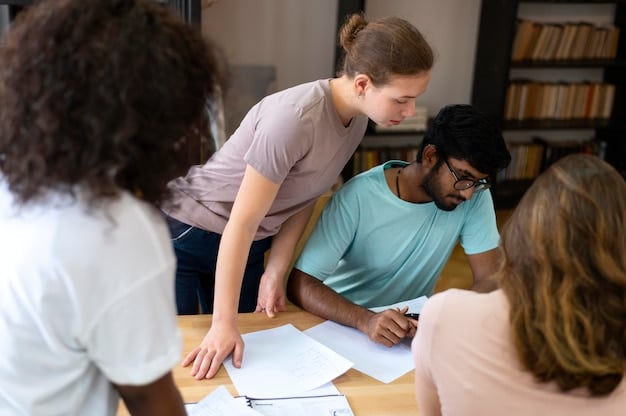 A group of volunteers from different organizations meeting around a table, reviewing documents and discussing project details. The atmosphere is focused and productive, with laptops, notebooks, and documents scattered across the table.