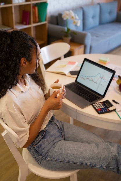 A person sitting at a desk, using a laptop to calculate their income. The scene is set in a home office, with financial documents and a calculator nearby. The individual appears focused and determined, symbolizing the effort involved in managing personal finances and understanding eligibility for healthcare subsidies.