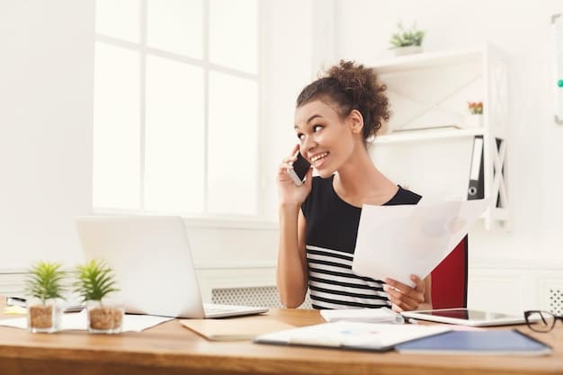 A person wearing a headset, smiling and talking on the phone while sitting at a desk with papers and medical bills organized neatly.