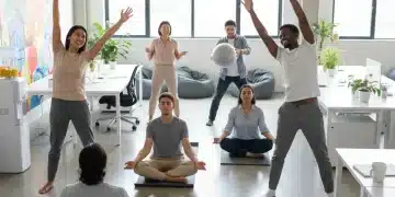 Empleados felices participando en un programa de bienestar laboral en una oficina moderna en España.